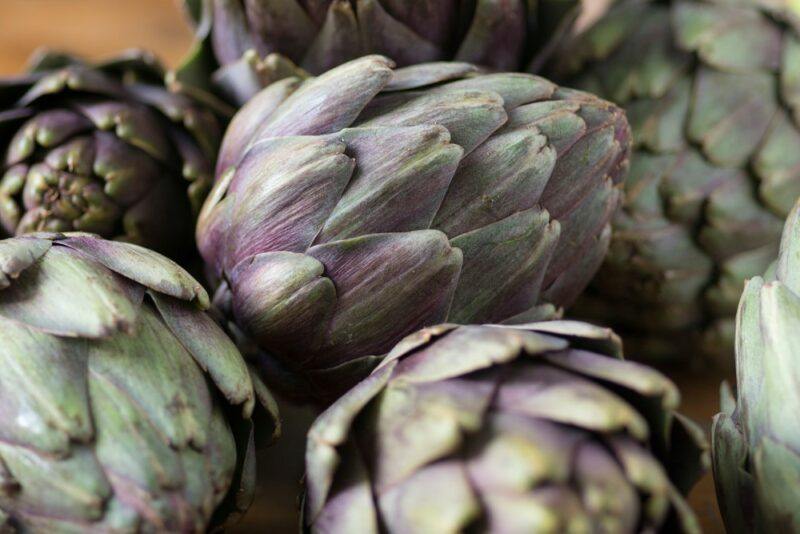 A pile of fresh artichokes on a wooden table