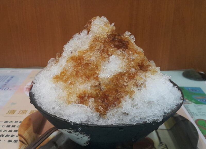 A black dish of ice with brown syrup in the flavor of Dr. Snow