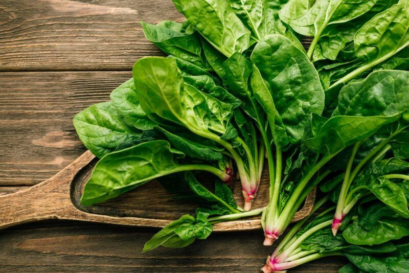 A wooden table with a bunch of fresh spinach