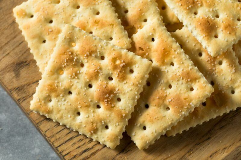 A wooden board with a pile of salted saltine crackers