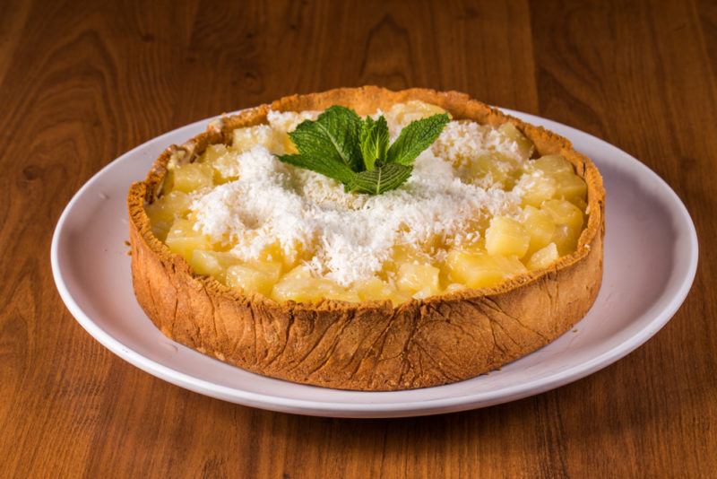 A pineapple pie on a white plate with coconut cream on top and a mint leaf