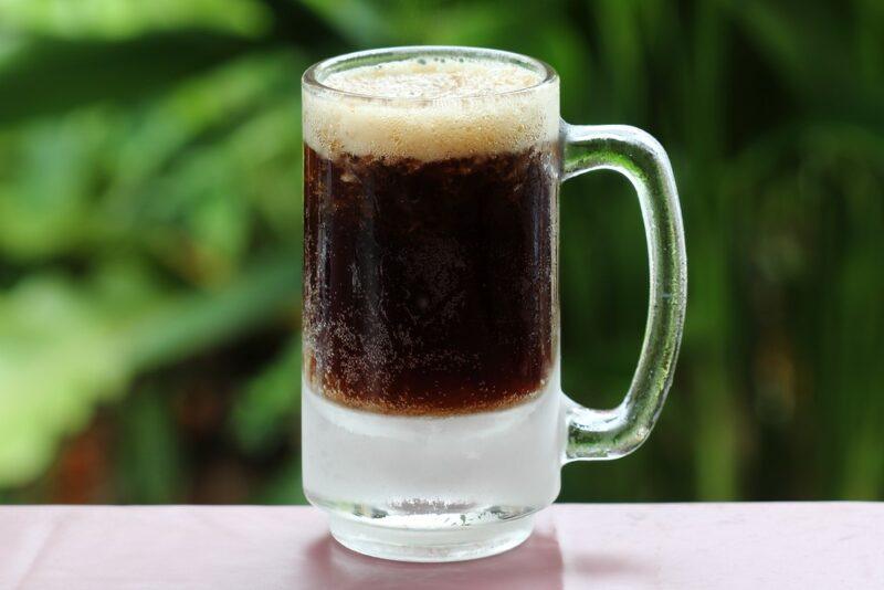 A mug of Fireball root beer on a table with green leaves in the background