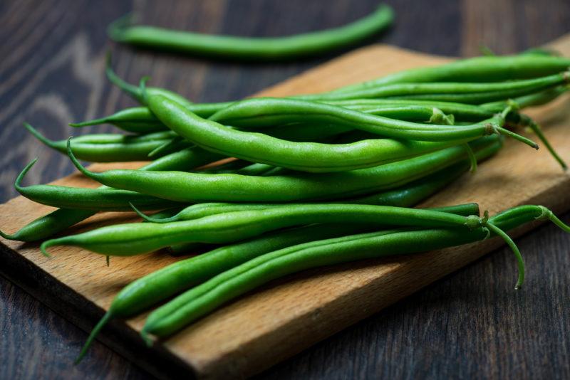 Fresh green beans on a wooden plank