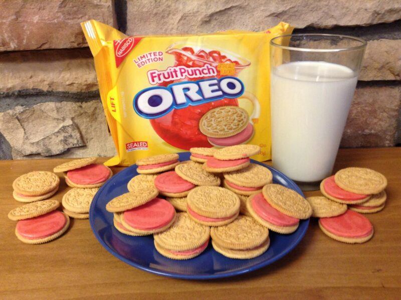 A blue plate with Fruit Punch Oreo cookies, next to a glass of milk