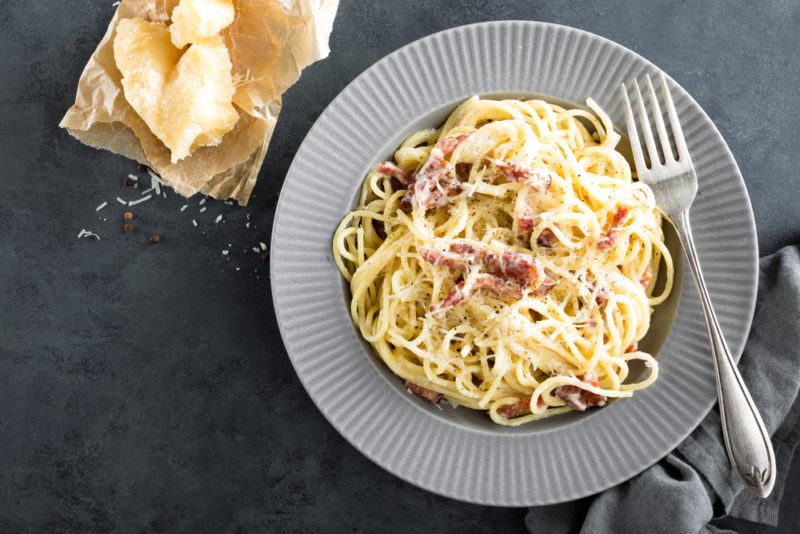 A gray plate with creamy spaghetti pasta next to a fork