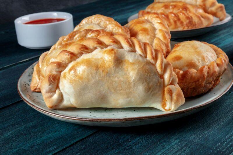 A plate with a few different empanadillas in front of dipping sauce and a second plate