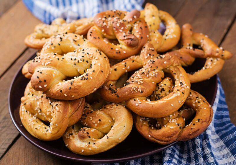 A pile of soft pretzels with poppy seeds on a blue and white cloth