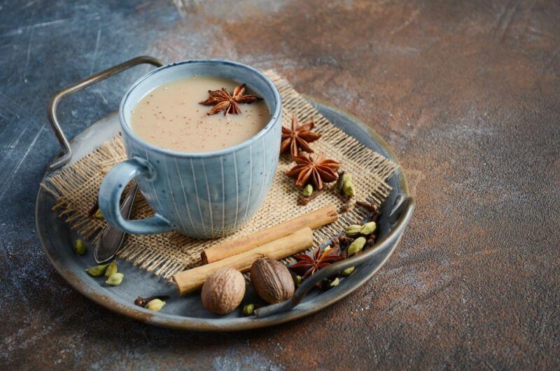 A light blue plate that contains spices, with a light blue mug of chai tea on it