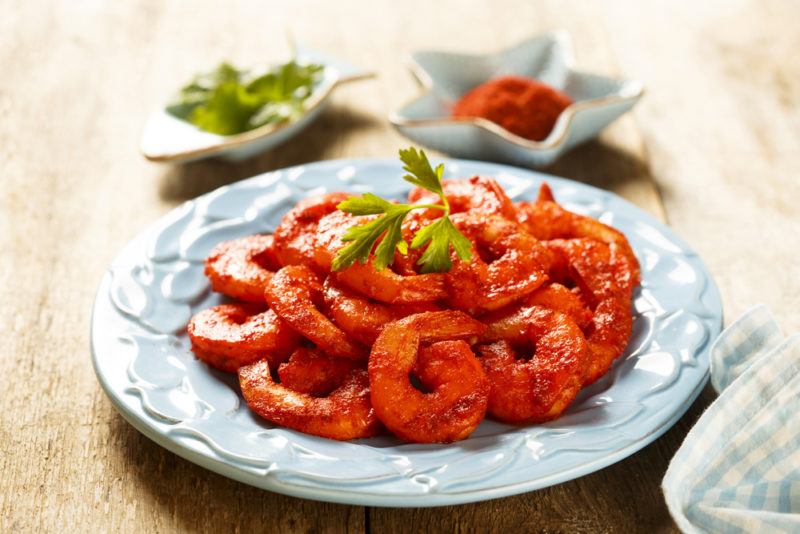 A plate of tandoori shrimp with seasonings on a wooden table