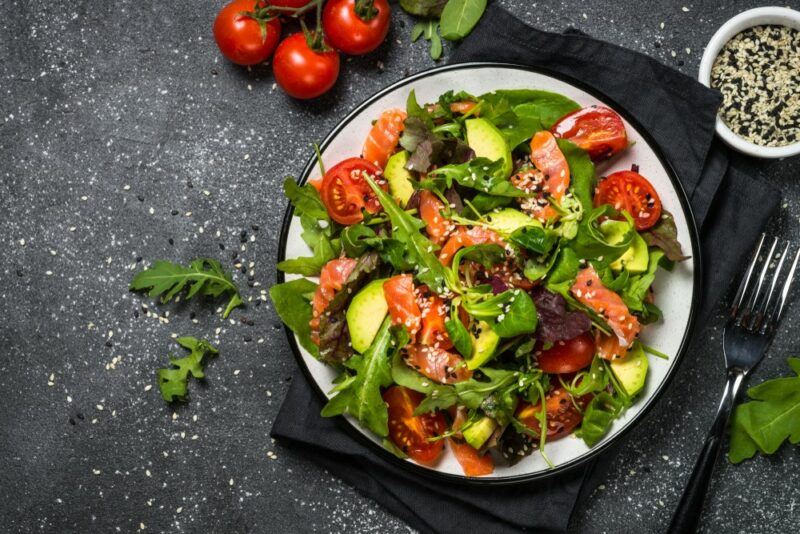 A large bowl of salad with avocados and fish