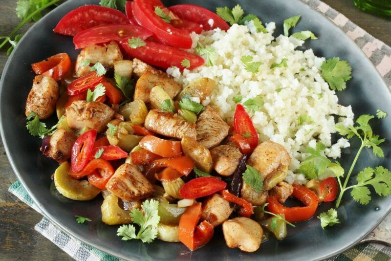 A gray dish filled with chicken, peppers, and cauliflower rice