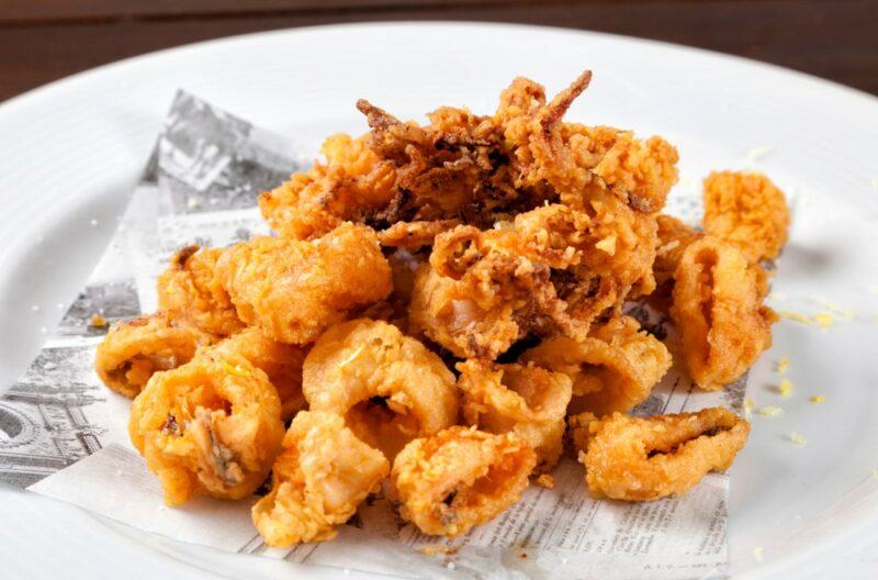 A white dish that contains various pieces of fried calamari