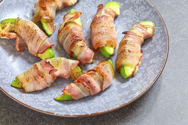 A gray plate with pieces of avocado wrapped in bacon