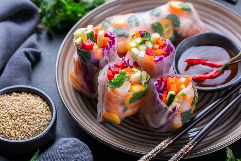 A plate with rice paper spring rolls, next to soy sauce and sesame seeds for dipping