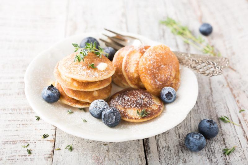 A white plate with small pancakes and blueberries