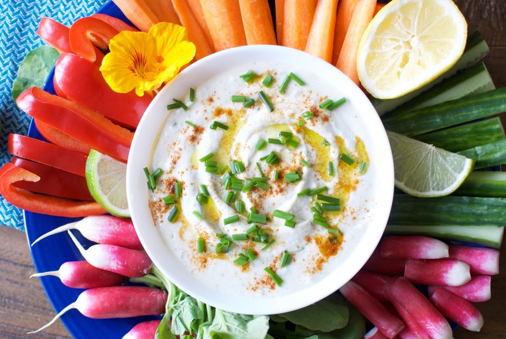 A large blue dish with cut veggies and a white bowl of dip