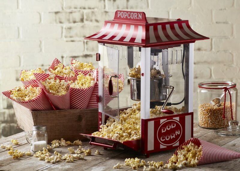 A movie style popcorn cart next to small bags of popcorn