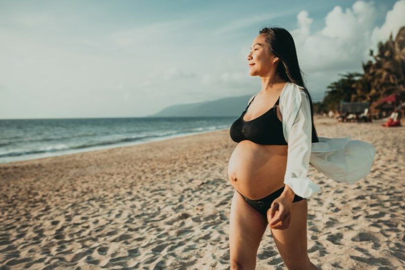 A pregnant woman walking on the beach