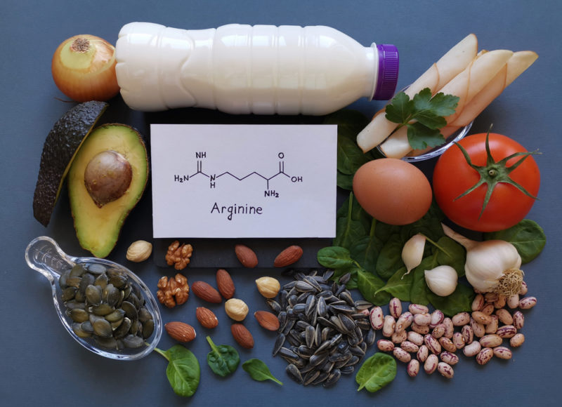 A selection of arginine rich foods on a table including avocados and milk