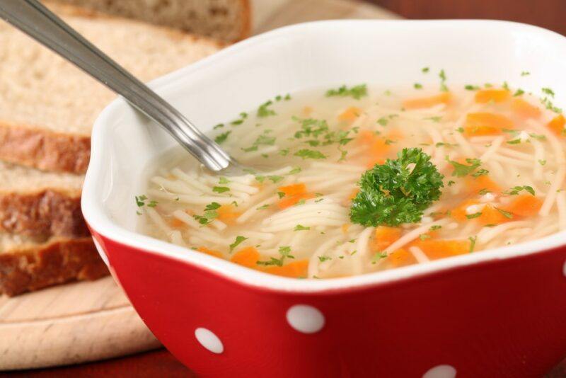 A red and white bowl filled with chicken soup called sopa de picadillo