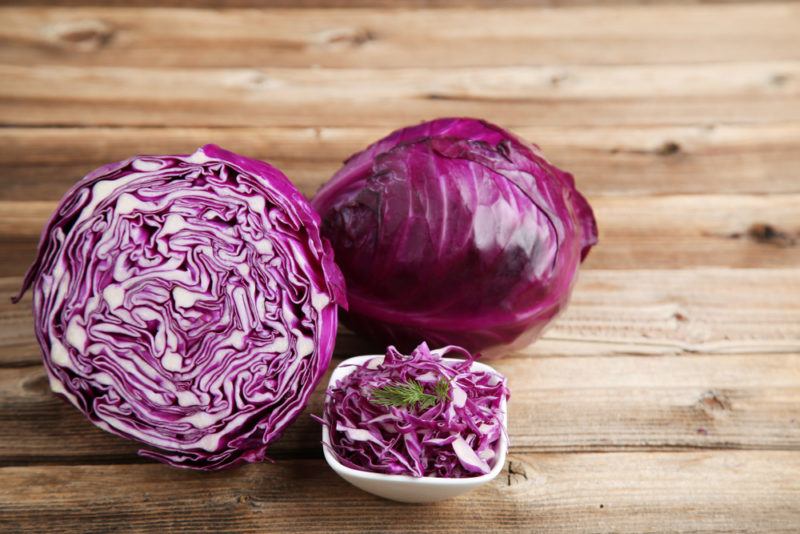 Half a red cabbage, a red cabbage and shredded cabbage in a small bowl