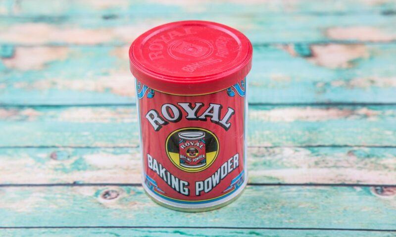 A light blue wooden table with a red container of baking powder