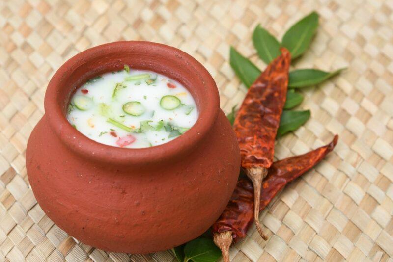 A terracotta bowl will chaach and herbs on the top