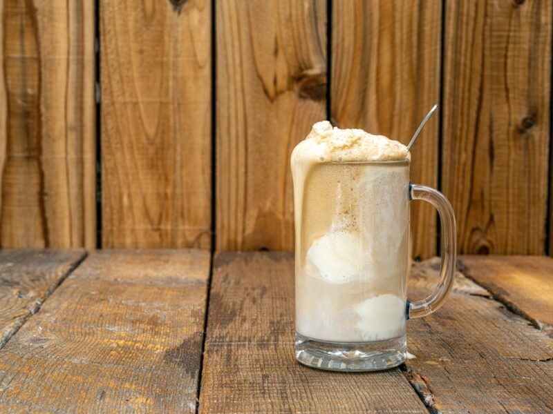 A cold mug containing a root beer float on a wooden floor