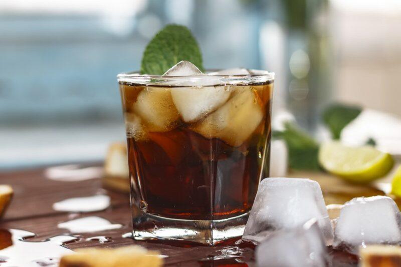 A single rum and coke cocktail on a table, with ice