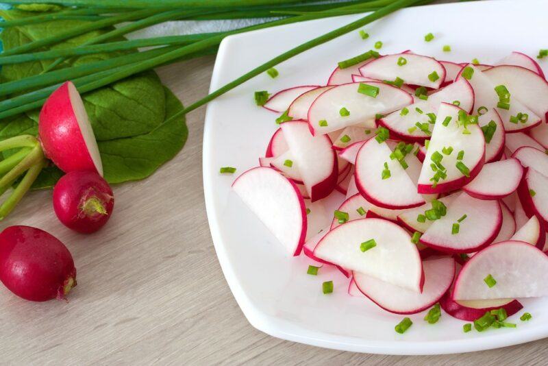 A white plate with sliced radishes