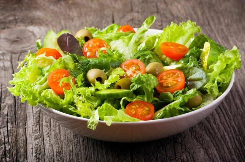 A large bowl filled with a lettuce salad and various vegetables