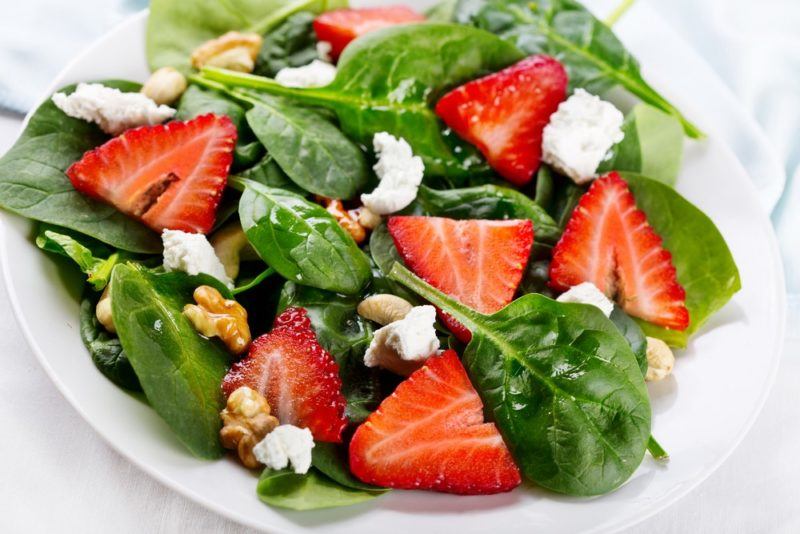 A vibrant salad made using feta, strawberries, and walnuts