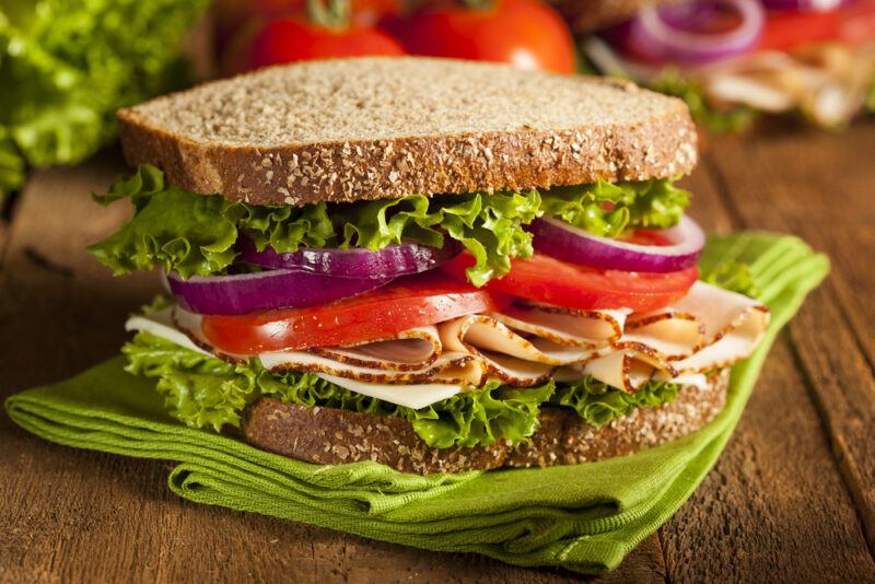 A large sandwich filled with shaved turkey and plenty of veggies, like lettuce, red onions, and tomatoes