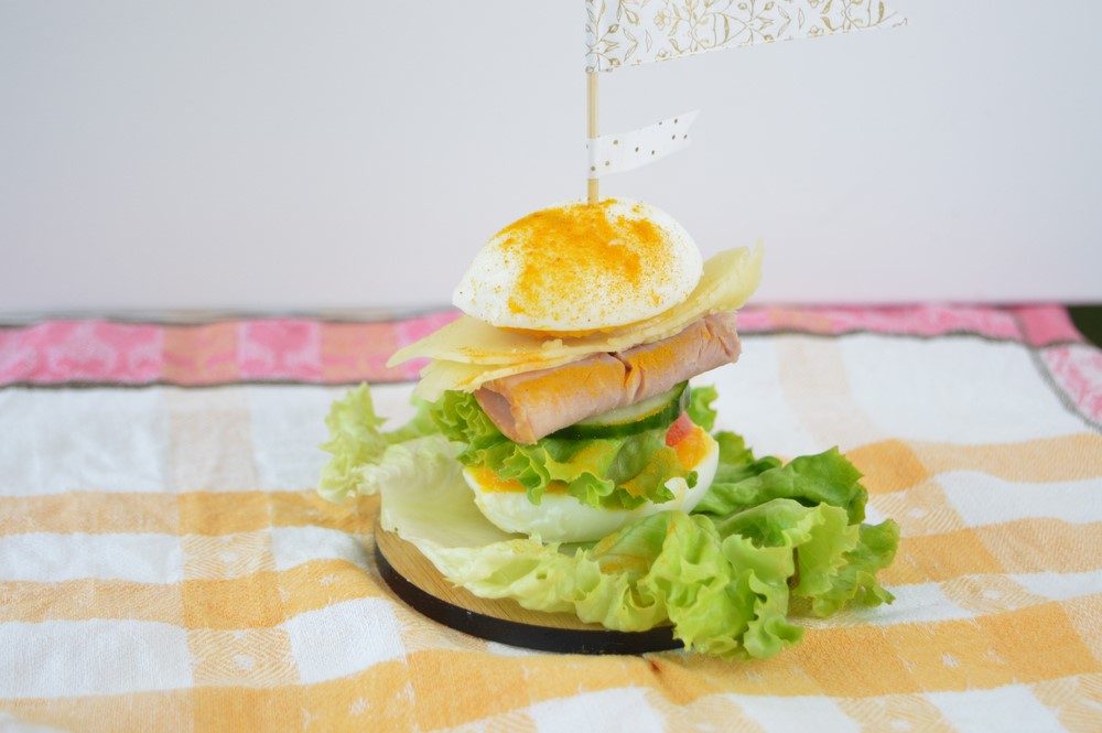 A sandwich made using eggs and salad