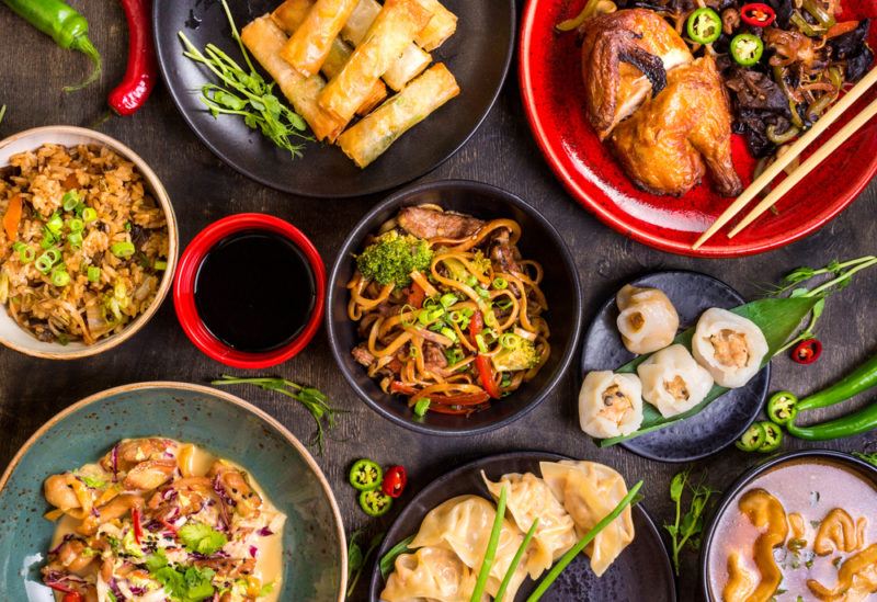 A black table with many small dishes of Chinese food