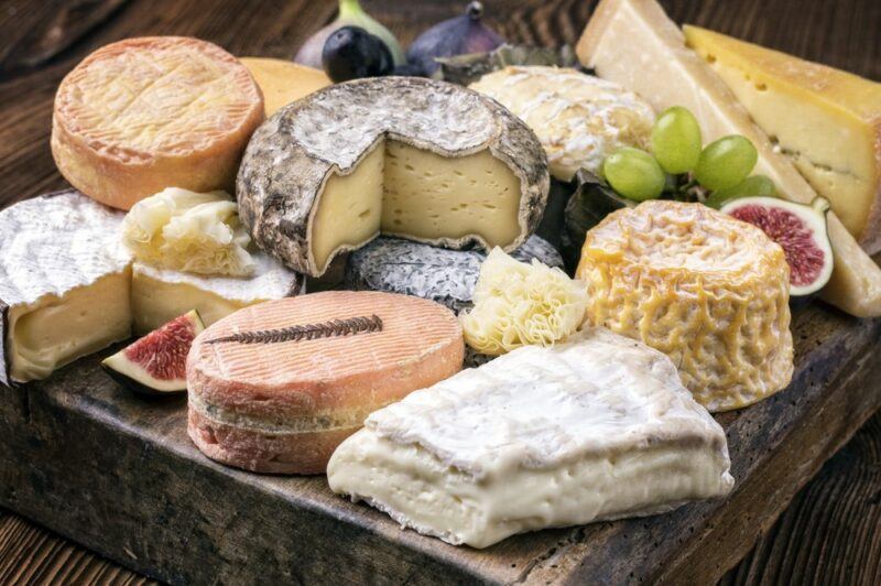 A wooden board containing a selection of French cheeses