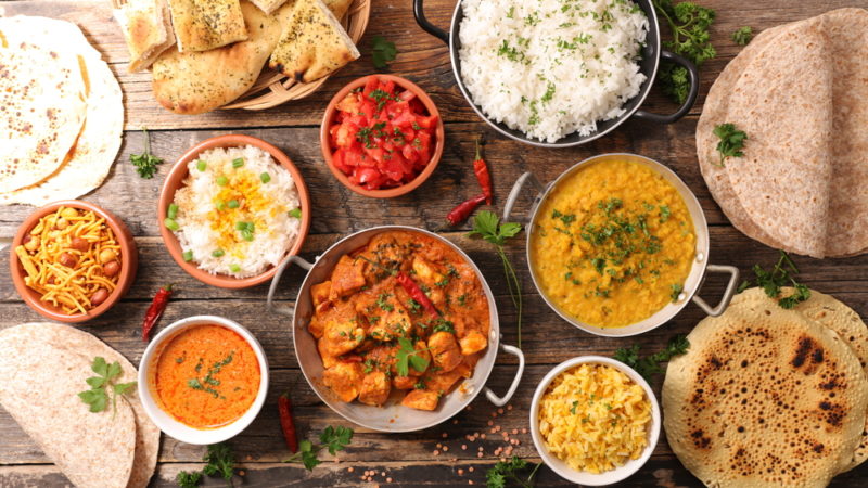 A selection of Indian curries on a table with rice and naan bread