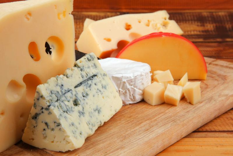 A wooden board with a selection of aged cheeses