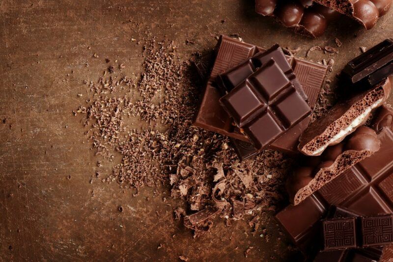 A brown table with pieces of chocolate and cocoa nibs