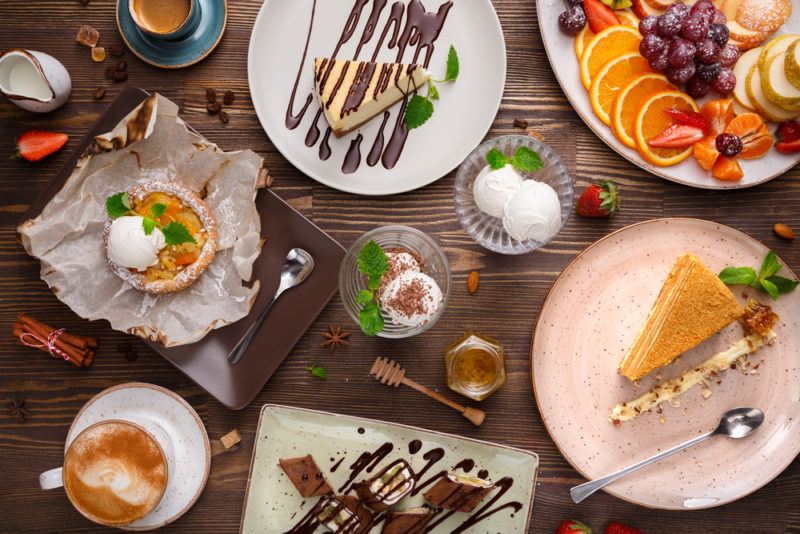 A selection of different desserts on plates and bowls on a wooden table