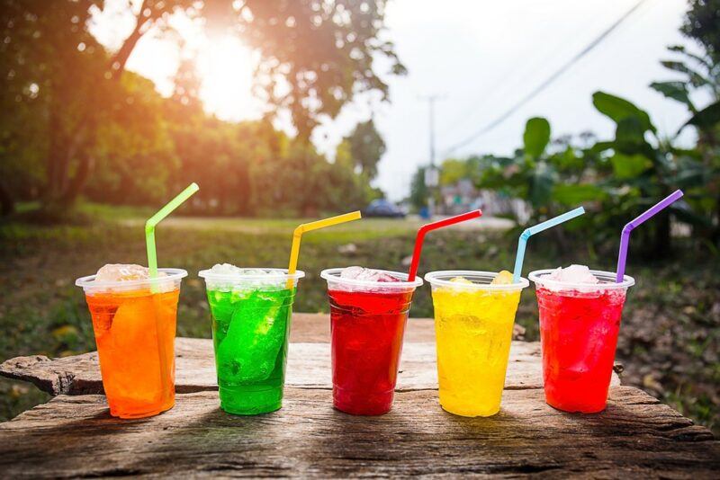 A selection of brightly colored plastic glasses containing loaded tea