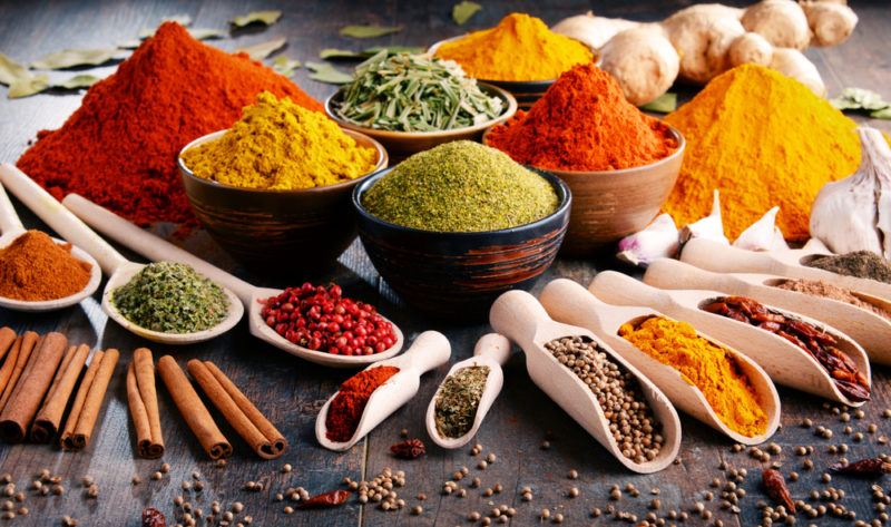 A table containing many different types of spices, most of which are in small bowls or wooden scoops