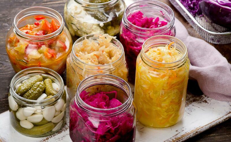 A selection of fermented vegetables in jars, including kimchi and pickled beets