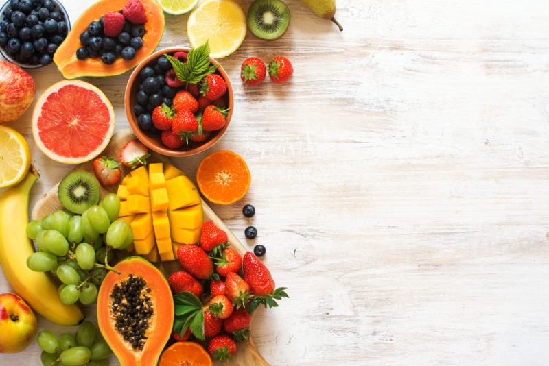 A wooden table with a flat lay of various fresh fruits