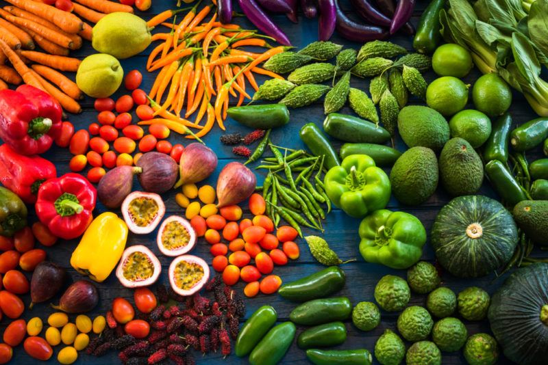 A selection of fresh fruit and vegetables on a table, in all colors