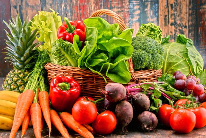 A selection of fresh fruit and vegetables surrounding a basket