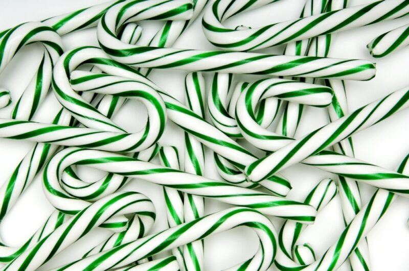 Green and white pickle candy canes against a white background