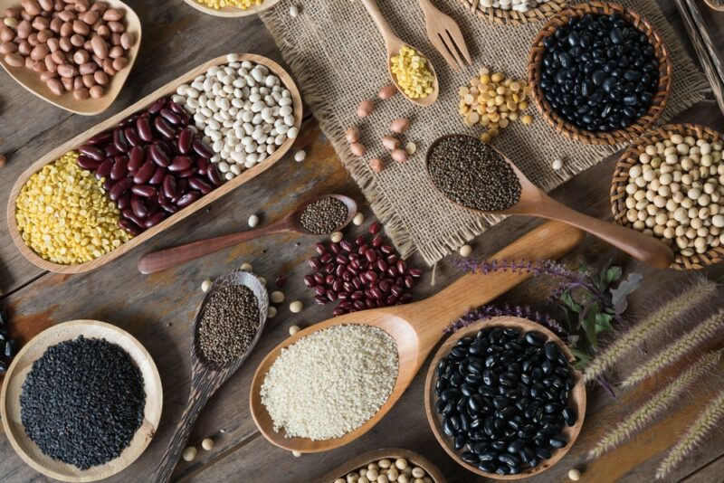 A collection of legumes and grains on a table in spoons and small dishes