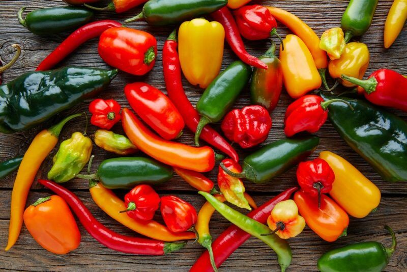 A table filled with many types of hot pepper, in various colors and shapes