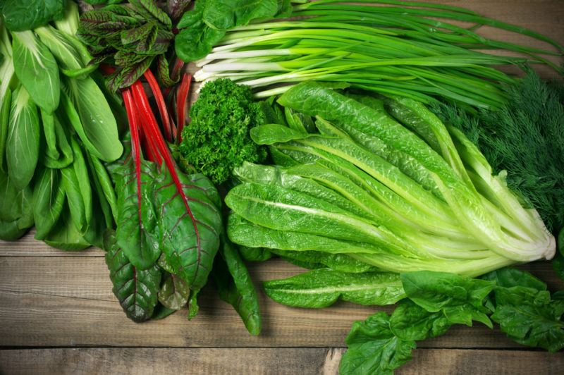 A selection of brightly colored leafy greens on a wooden table